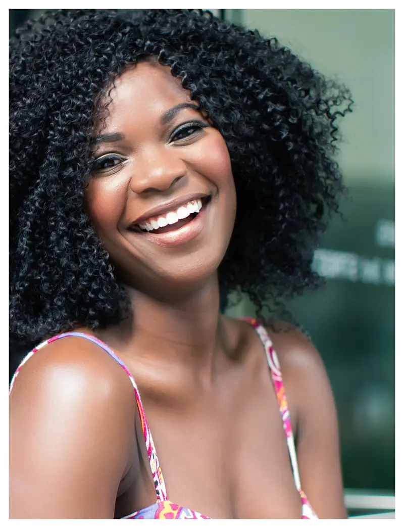 Mulher de cabelo cacheado sorrindo